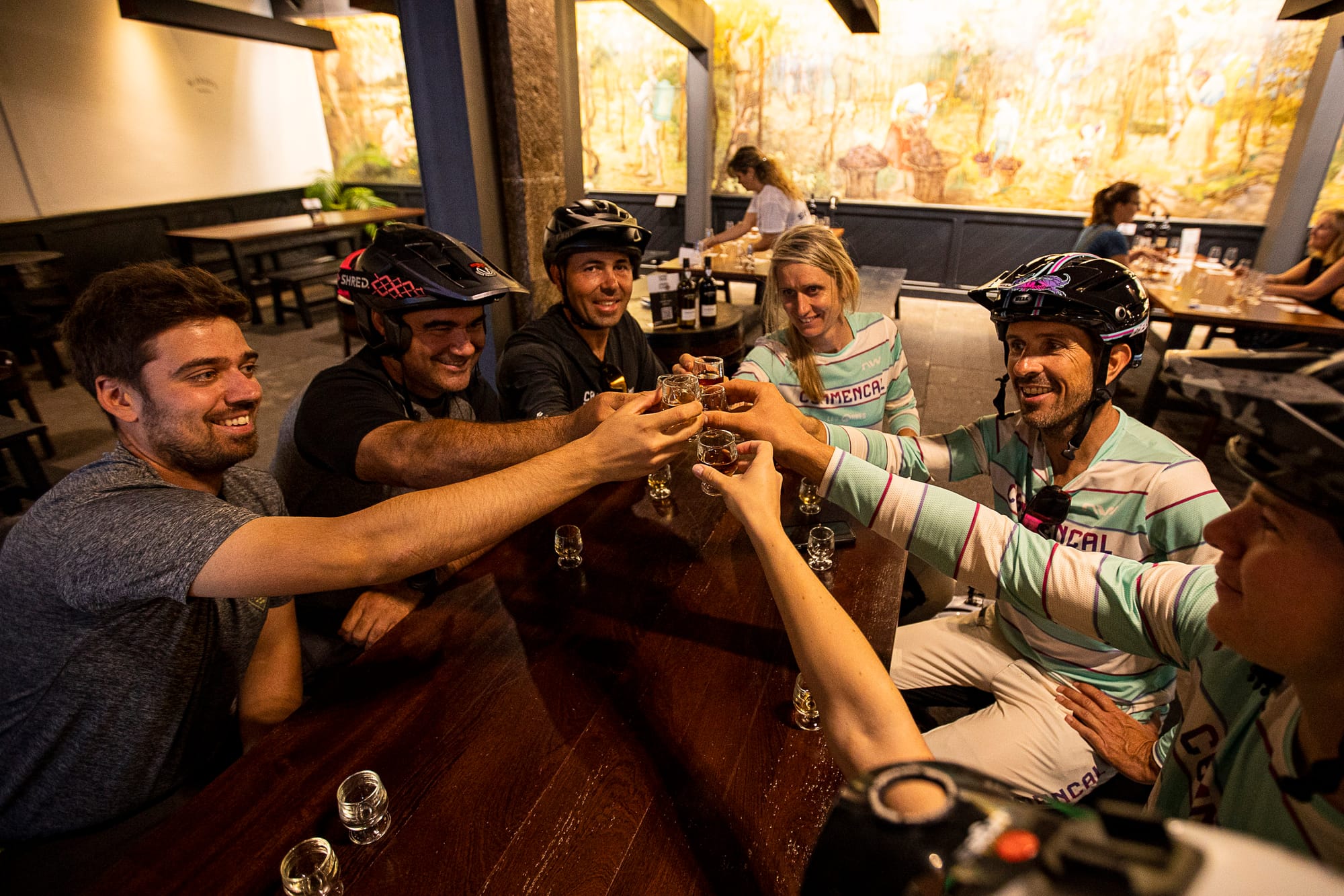 Riders in Commençal jerseys raising a toast around the table