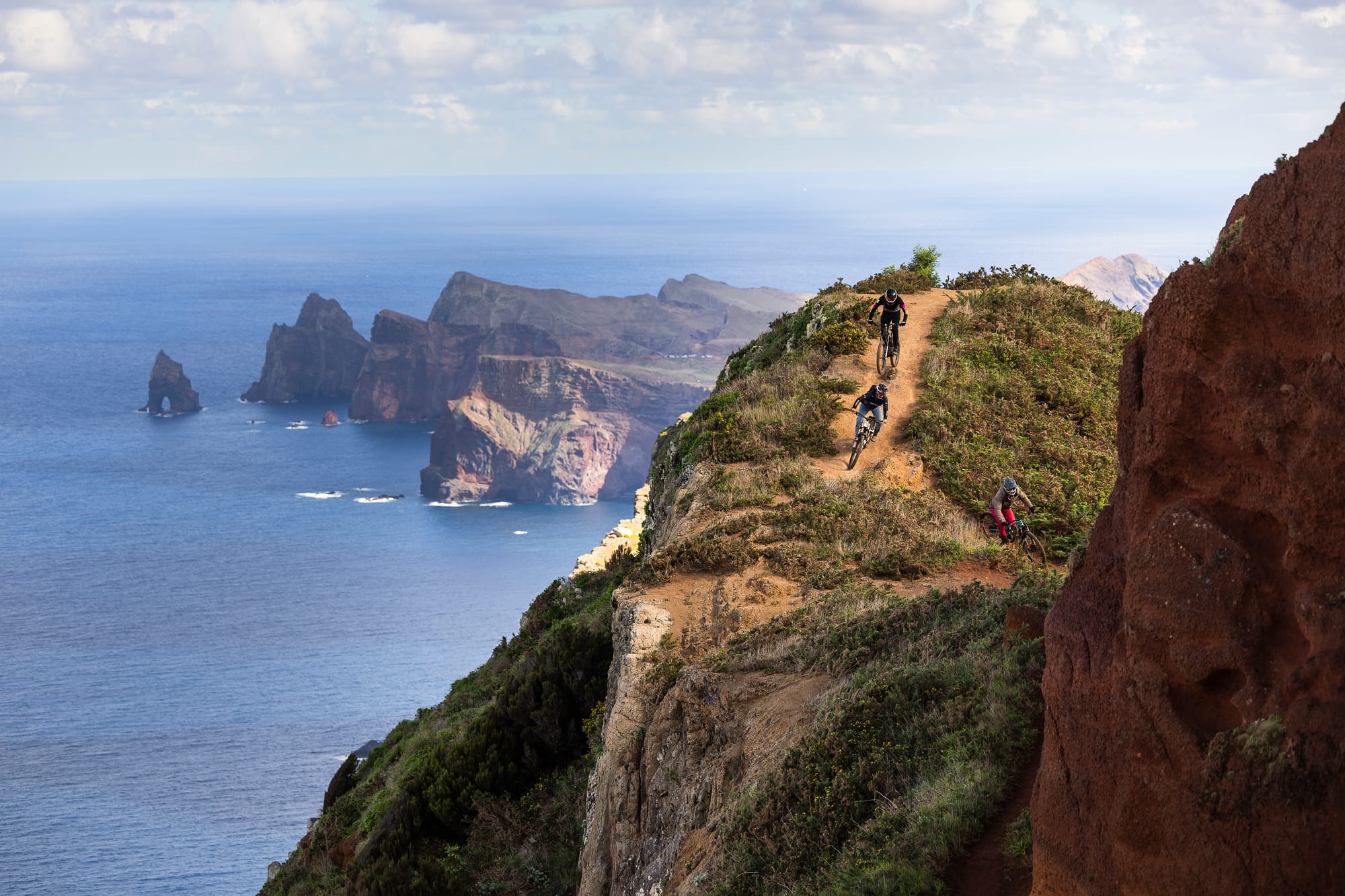 Riders on a ridge-top trail high above Madeira's sea cliffs