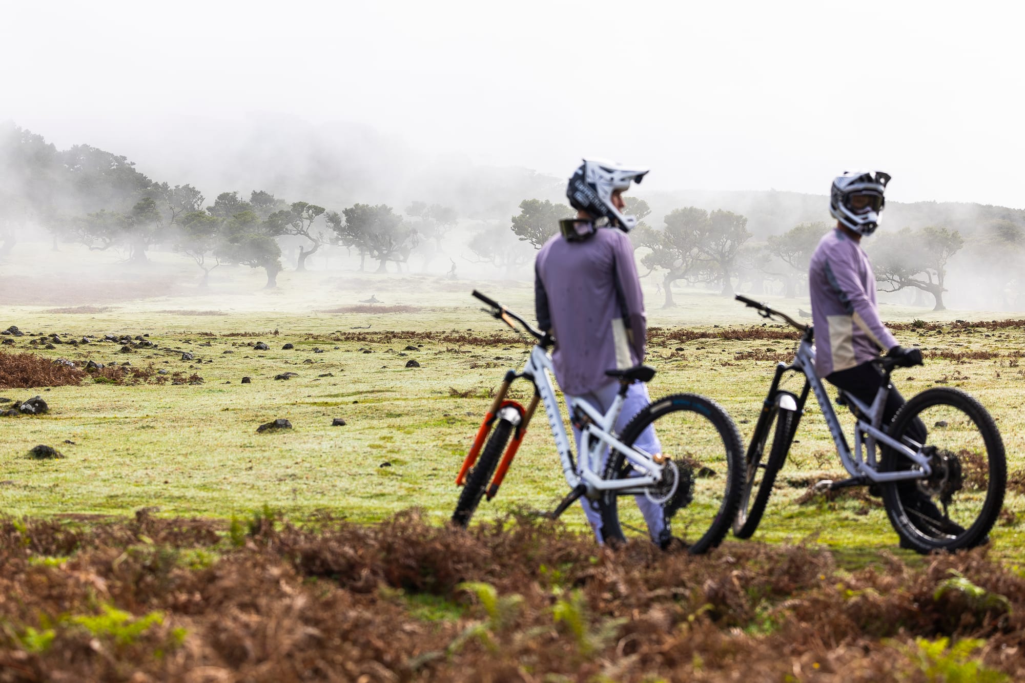 Two Commençal riders with their bikes on the misty Fanal plateau